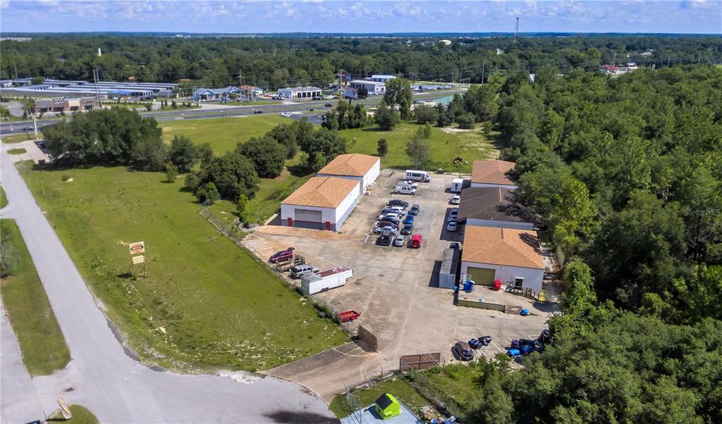 An aerial view shows commercial warehouse buildings with parking lots surrounded by trees and grass — 10857 SW 91 AVENUE UNIT C, OCALA, FL