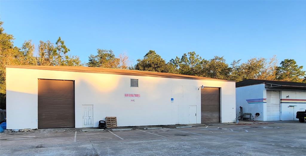 A white commercial warehouse building with two roll-up doors and a parking lot — 10857 SW 91 AVENUE UNIT C, OCALA, FL