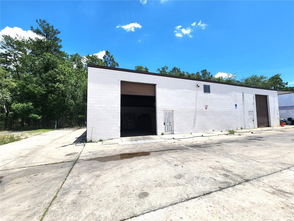 A white concrete block industrial building features two roll-up doors and a single entry door — 10857 SW 91 AVENUE UNIT C, OCALA, FL