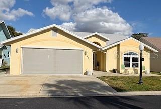 A yellow single-story house features a two-car garage with a screen and a front lawn — 422 HARBOURVIEW DRIVE, HAINES CITY, FL