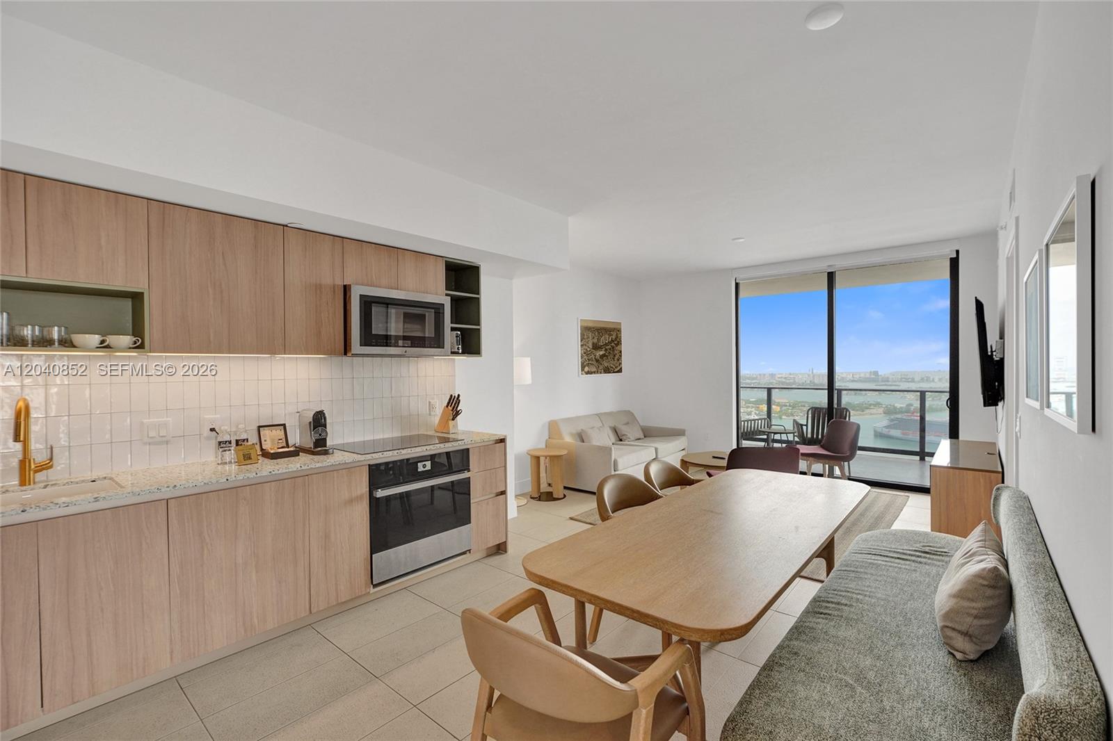 A modern kitchen and dining area features light wood cabinetry and a balcony with water views — 159 NE 6th St # 3916, Miami FL 33132, MIAMI, FL