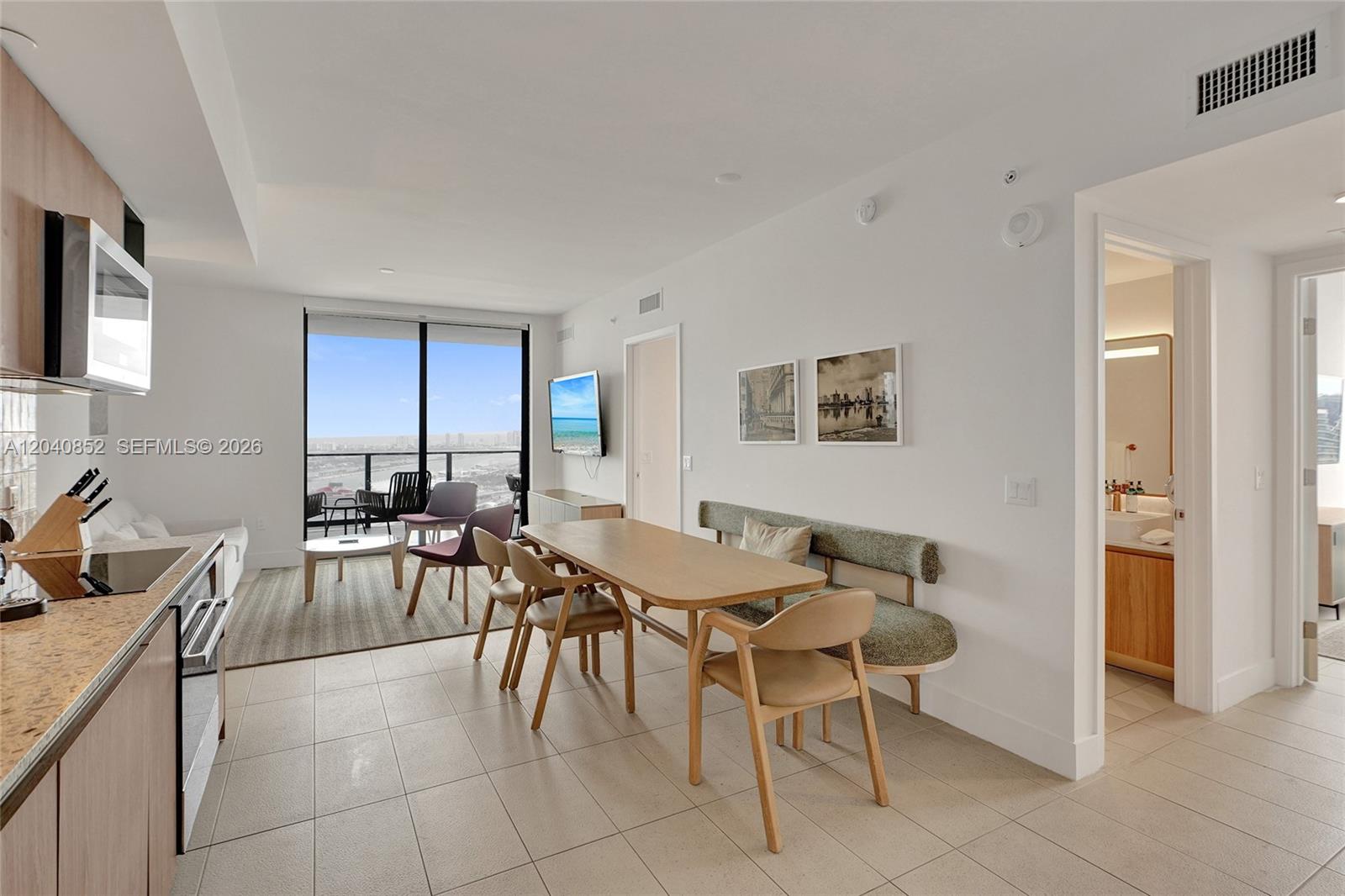 A modern kitchen and dining area features light wood cabinetry, tile flooring, and balcony views — 159 NE 6th St # 3916, Miami FL 33132, MIAMI, FL