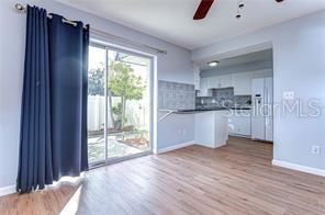 A living area with wood-look flooring leads to a kitchen with white cabinets and appliances — 1799 N HIGHLAND AVENUE UNIT 132, CLEARWATER, FL
