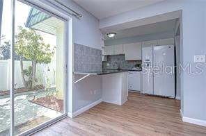 This kitchen features white cabinets, a breakfast bar, and a sliding glass door to outside — 1799 N HIGHLAND AVENUE UNIT 132, CLEARWATER, FL