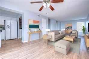 A living room with light wood floors, a beige sofa, and an open kitchen area — 1799 N HIGHLAND AVENUE UNIT 132, CLEARWATER, FL