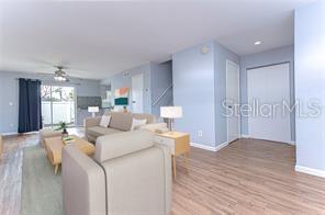A living room features light wood flooring, a beige sofa, and a sliding glass door — 1799 N HIGHLAND AVENUE UNIT 132, CLEARWATER, FL