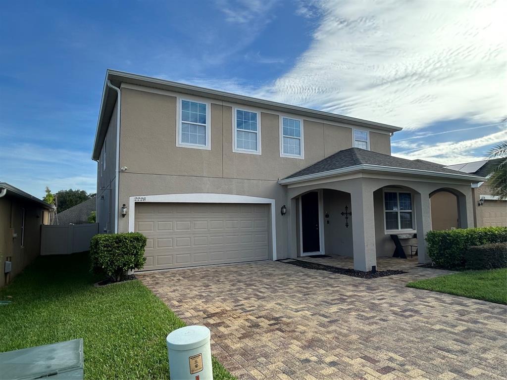 A two-story house with a beige stucco exterior, a two-car garage, and a paved driveway — 2228 NAPONE LANE, MINNEOLA, FL