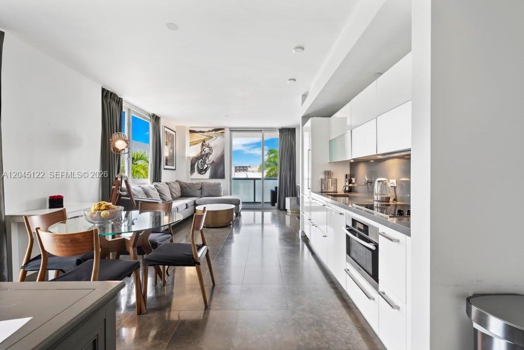A modern open-concept living area features a kitchen with white cabinetry and a dining space — 220 21st St # 401, Miami Beach FL 33139, MIAMI BEACH, FL