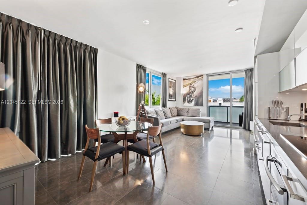 A modern open-concept living and dining area features tile floors, a kitchen, and balcony access — 220 21st St # 401, Miami Beach FL 33139, MIAMI BEACH, FL