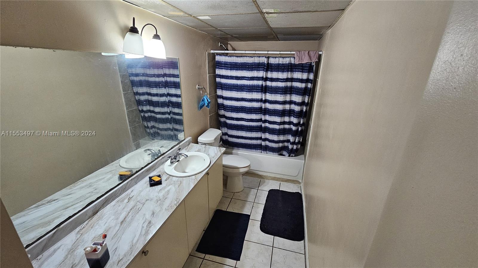 A bathroom features a marble-patterned vanity, a toilet, and a shower with a striped curtain — 2800 NW 56th Ave # A403, Lauderhill FL 33313, LAUDERHILL, FL