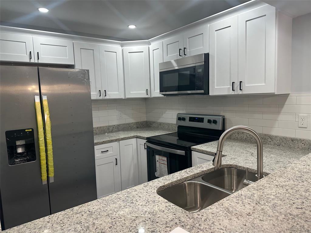 A kitchen featuring white cabinets, stainless steel appliances, granite countertops, and a double-basin sink — 3281 BENEVA ROAD UNIT 204, SARASOTA, FL