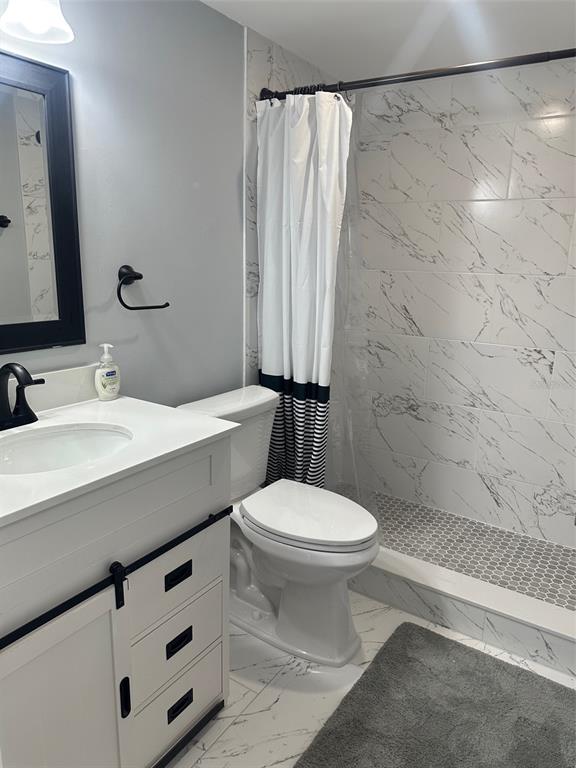 A bathroom features a white vanity, a toilet, and a walk-in shower with marble-look tiles — 3281 BENEVA ROAD UNIT 204, SARASOTA, FL