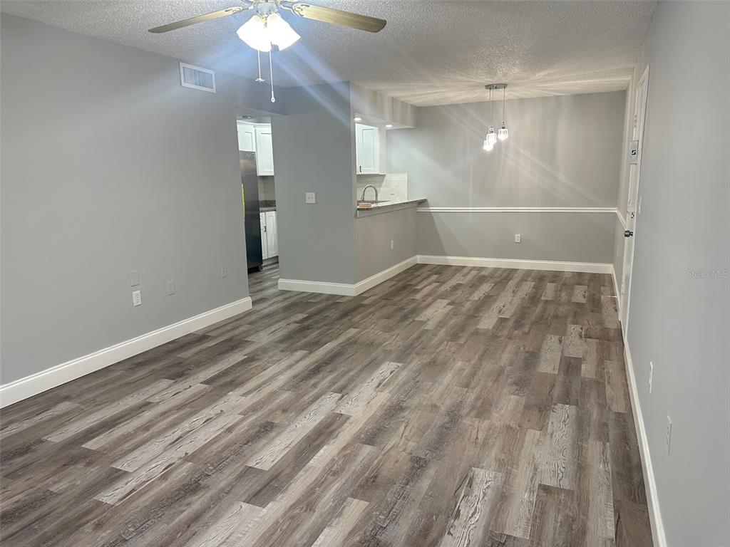 An open-concept living and dining area features gray walls, wood-look flooring, and a kitchen pass-through — 3281 BENEVA ROAD UNIT 204, SARASOTA, FL