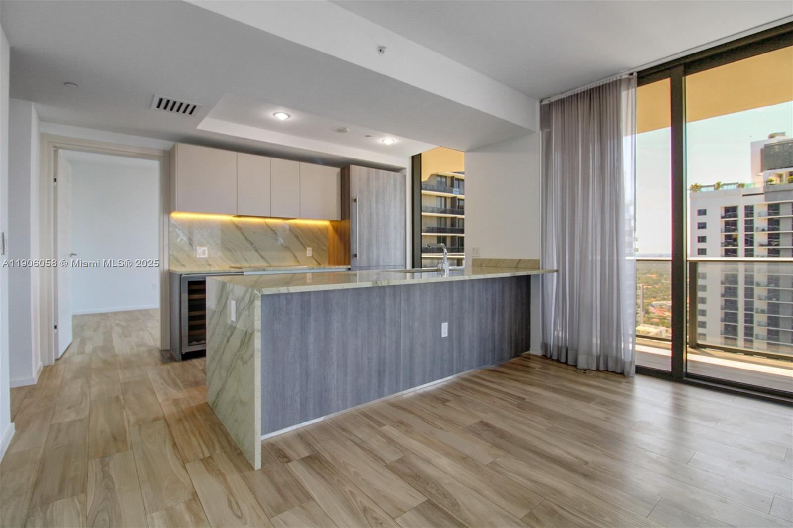 A modern kitchen features a marble island, wood-toned cabinetry, and a balcony with city views — 801 S Miami Ave # 4309, Miami FL 33130, MIAMI, FL