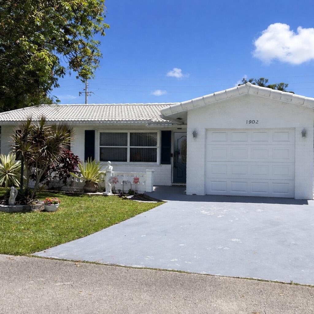 A white, single-story house with a garage and a small front lawn under a blue sky — 1902 SW 22nd Avenue, Boynton Beach FL 33426, BOYNTON BEACH, FL