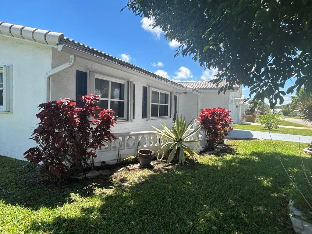 A white house exterior features a decorative concrete wall, red shrubs, and a large agave — 1902 SW 22nd Avenue, Boynton Beach FL 33426, BOYNTON BEACH, FL