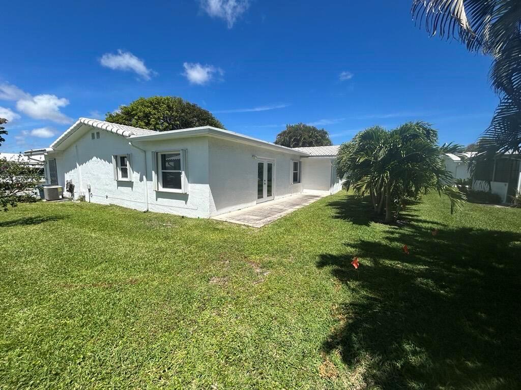 A white, single-story house with a tiled roof, patio, and lawn under a blue sky — 1902 SW 22nd Avenue, Boynton Beach FL 33426, BOYNTON BEACH, FL