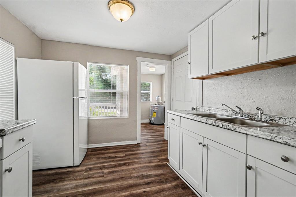 A kitchen with white cabinets, granite countertops, a white refrigerator, and wood-look flooring — 828 E 145TH AVENUE, TAMPA, FL