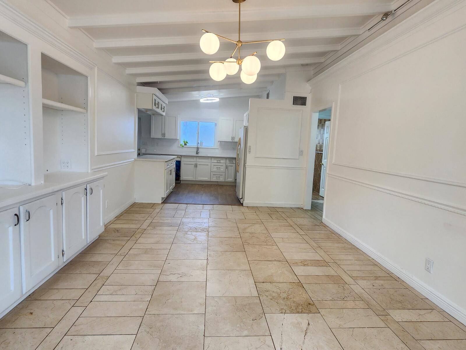 A white kitchen and dining area features tile flooring, a modern chandelier, and built-in cabinetry — 305 S Loxahatchee Drive, Jupiter FL 33458, JUPITER, FL
