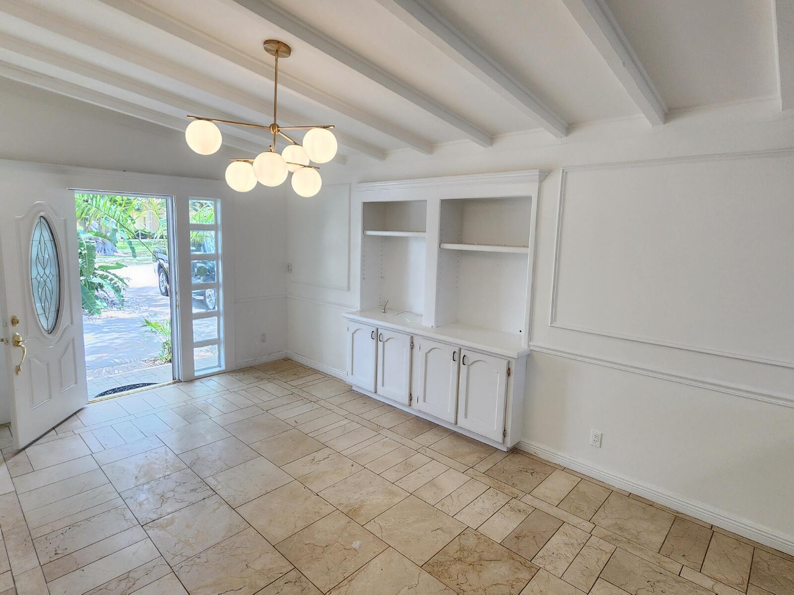 A bright room features white built-in cabinets, a modern chandelier, and light-colored tile flooring — 305 S Loxahatchee Drive, Jupiter FL 33458, JUPITER, FL