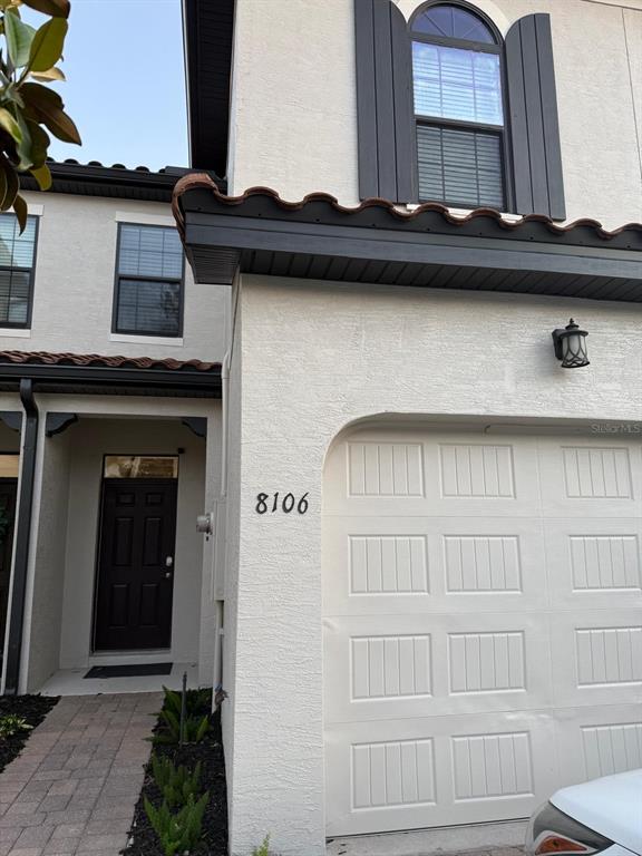 The exterior of a two-story townhouse features a white stucco facade, a garage, and a walkway — 8106 ROSEVILLE ROAD, DAVENPORT, FL