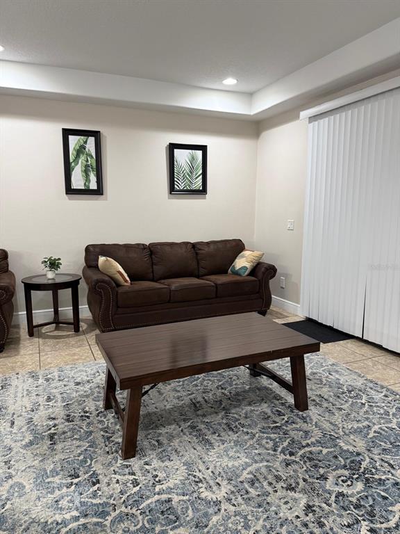 A living room features a brown leather sofa, a wooden coffee table, and patterned rug — 8106 ROSEVILLE ROAD, DAVENPORT, FL