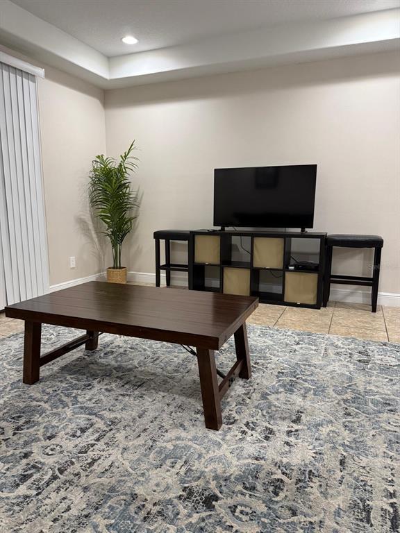 A living room features a dark wood coffee table, a television stand, and a patterned rug — 8106 ROSEVILLE ROAD, DAVENPORT, FL