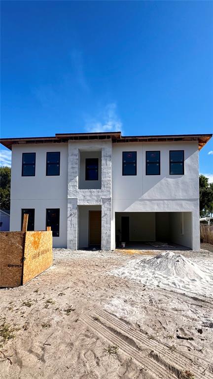 A two-story modern house features a white stucco exterior, stone accents, and a paved driveway — 803 W WOODLAWN AVENUE, TAMPA, FL
