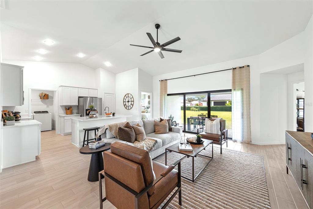 A bright open-concept living room features light tile floors, a modern ceiling fan, and kitchen — 3445 W DITTANY DRIVE, CITRUS SPRINGS, FL