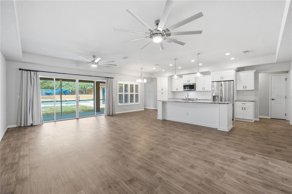 A view from a red front door into an open-concept living area with wood-look flooring — 13403 LELANI DRIVE, WEEKI WACHEE, FL