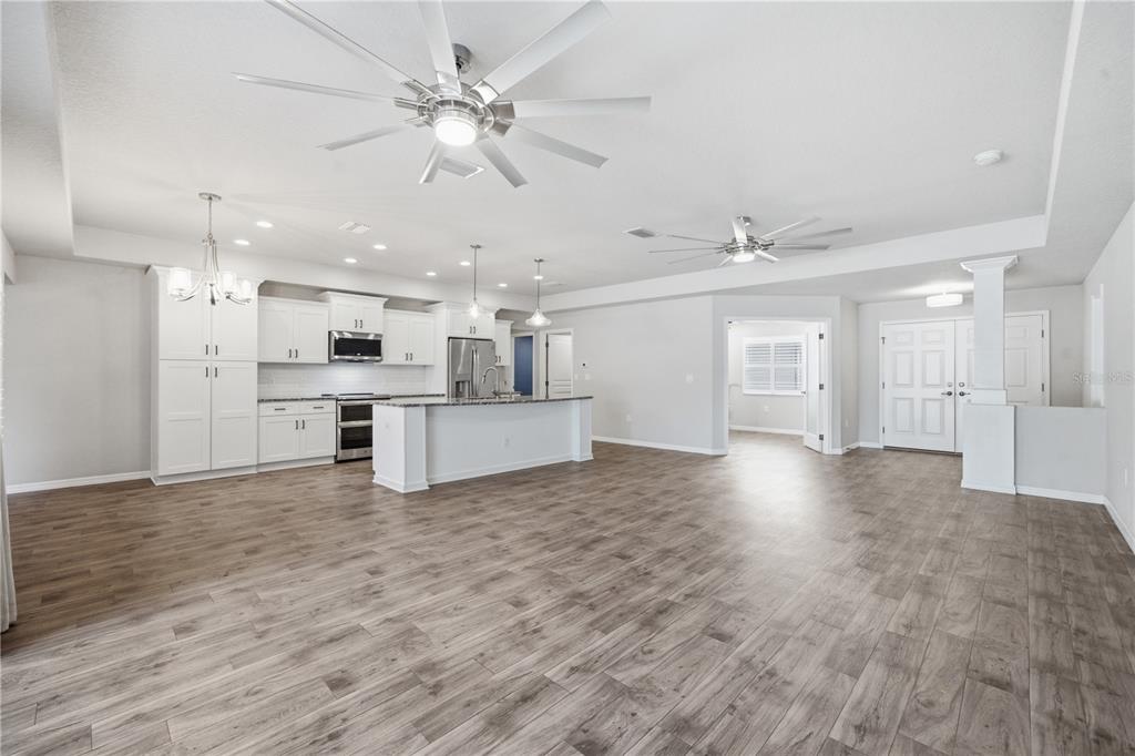 A spacious open-concept kitchen and living area with wood-look tile flooring and ceiling fans — 13403 LELANI DRIVE, WEEKI WACHEE, FL