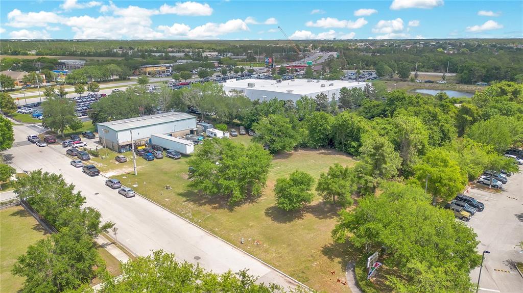 An aerial view shows a vacant grassy lot situated between a commercial building and parking — 0 LIONS COURT, KISSIMMEE, FL