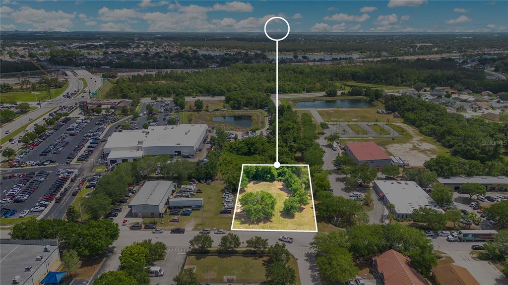 An aerial view shows a vacant, tree-covered lot outlined in white within a commercial area — 0 LIONS COURT, KISSIMMEE, FL