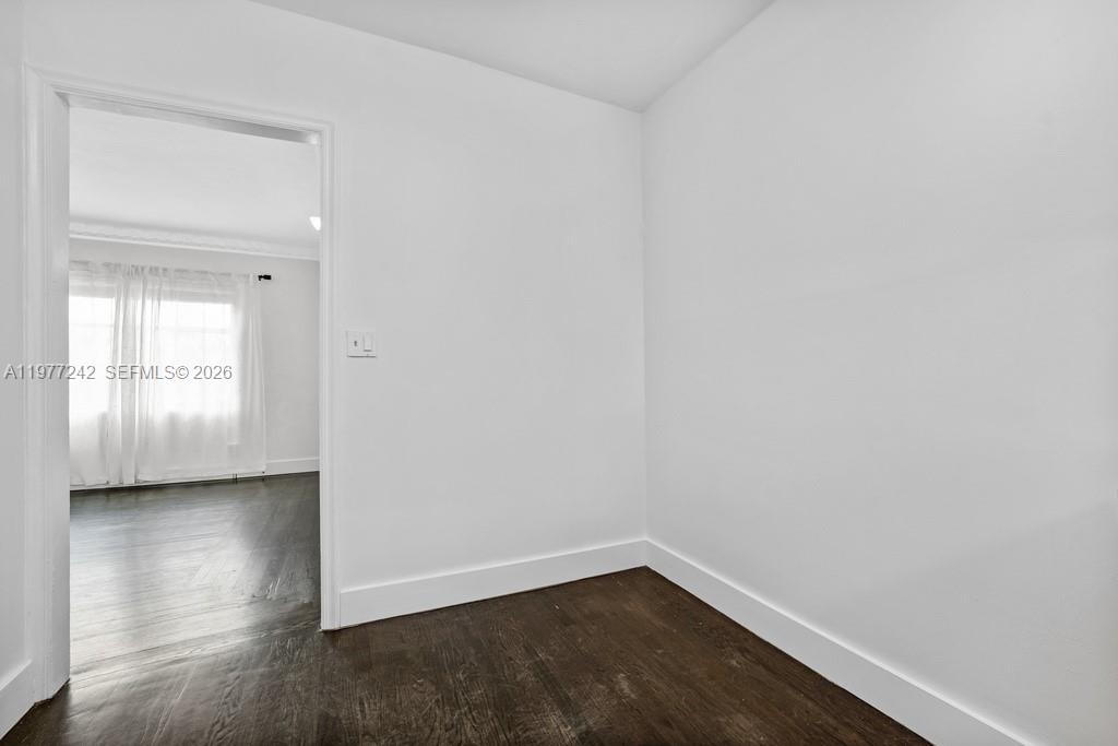 A small, empty room with white walls and dark wood flooring leads into another room — 846 Jefferson Ave # 8, Miami Beach FL 33139, MIAMI BEACH, FL
