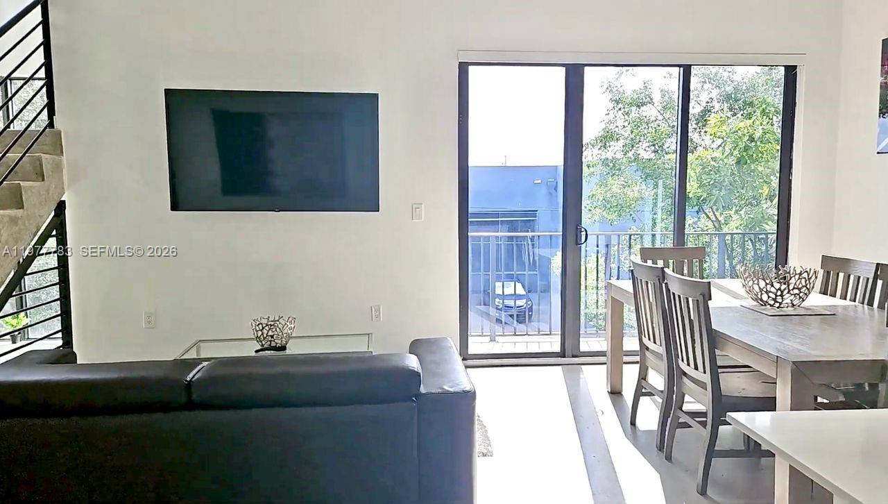 A living and dining area features a black sofa, wall-mounted television, and sliding glass doors — 7105 NE 4 Ct, Miami FL 33138, MIAMI, FL