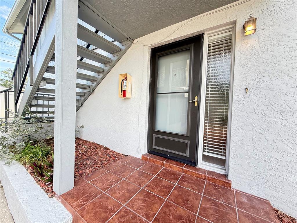 A tiled entryway features a dark-framed door, a side window, and a wall-mounted fire extinguisher — 1960 UNION STREET UNIT 41, CLEARWATER, FL