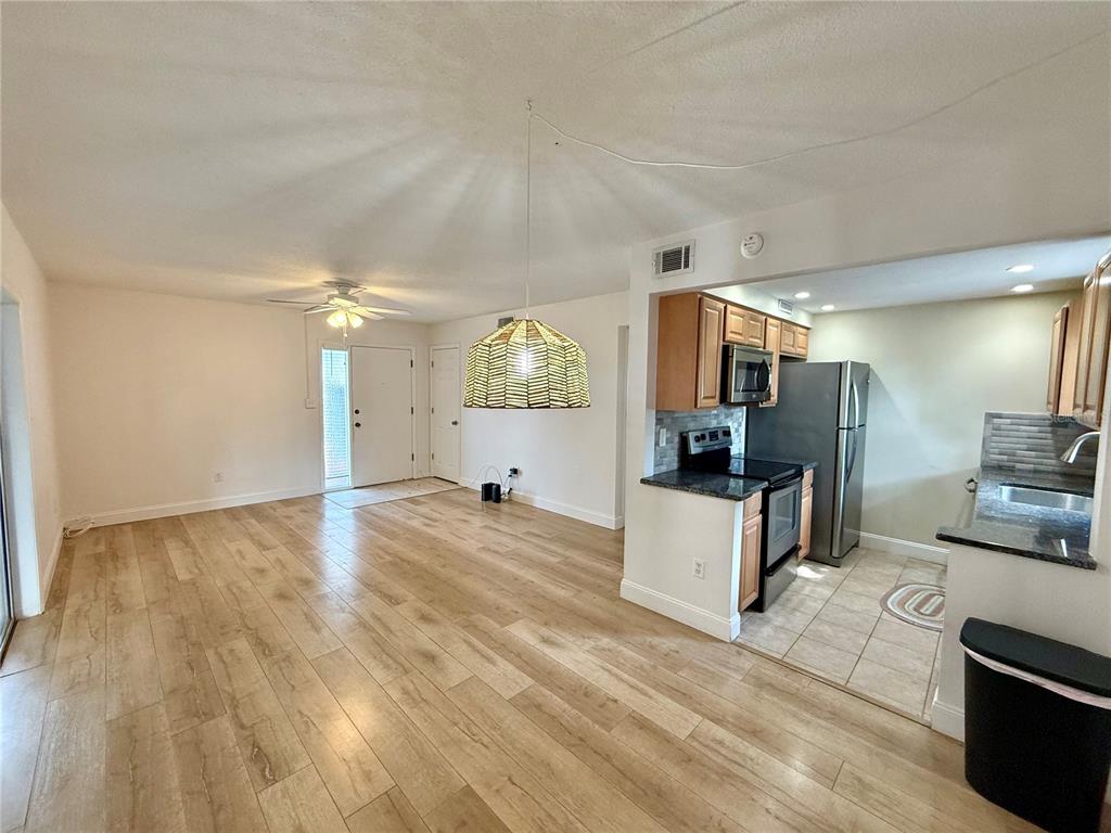 A living room with wood-look flooring flows into an open kitchen with stainless steel appliances — 1960 UNION STREET UNIT 41, CLEARWATER, FL
