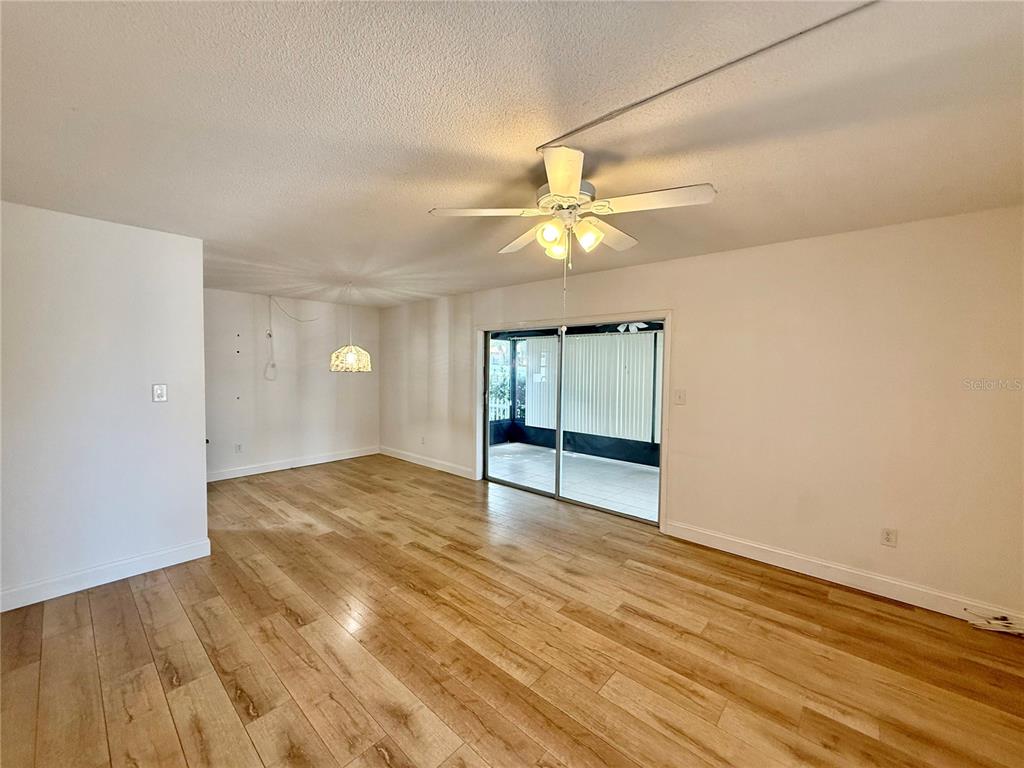 An empty living room features light wood-look flooring, a ceiling fan, and sliding glass doors — 1960 UNION STREET UNIT 41, CLEARWATER, FL