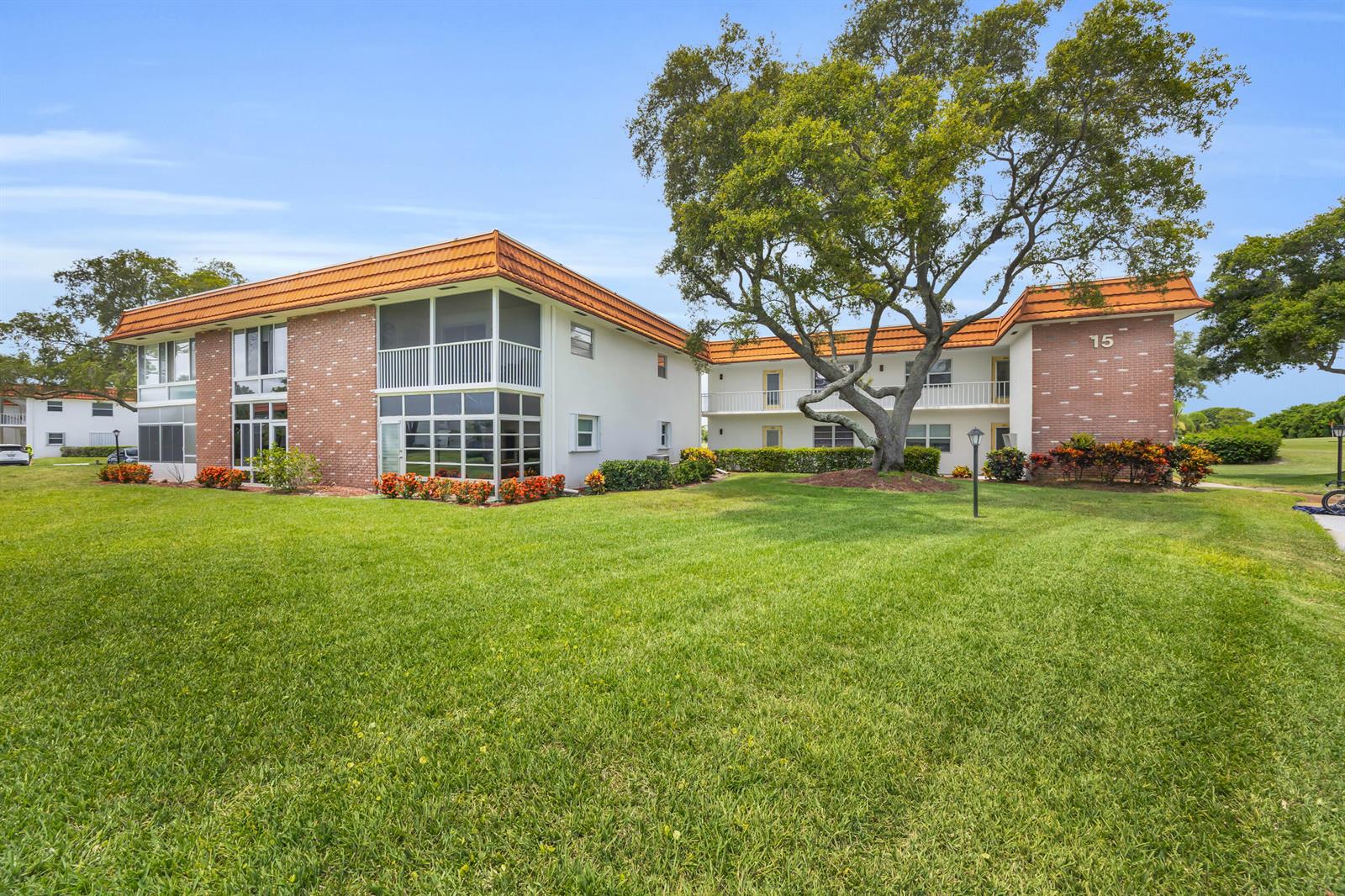 A two-story apartment building with brick accents, a tiled roof, and a large oak tree — 1225 NW 21st Street # 1502, Stuart FL 34994, STUART, FL
