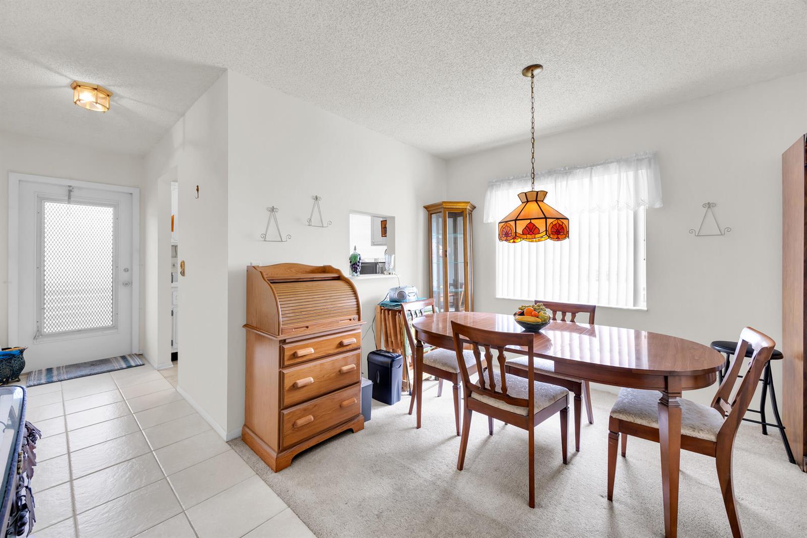 A dining room with a wooden table, chairs, a roll-top desk, and a hanging lamp — 1225 NW 21st Street # 1502, Stuart FL 34994, STUART, FL