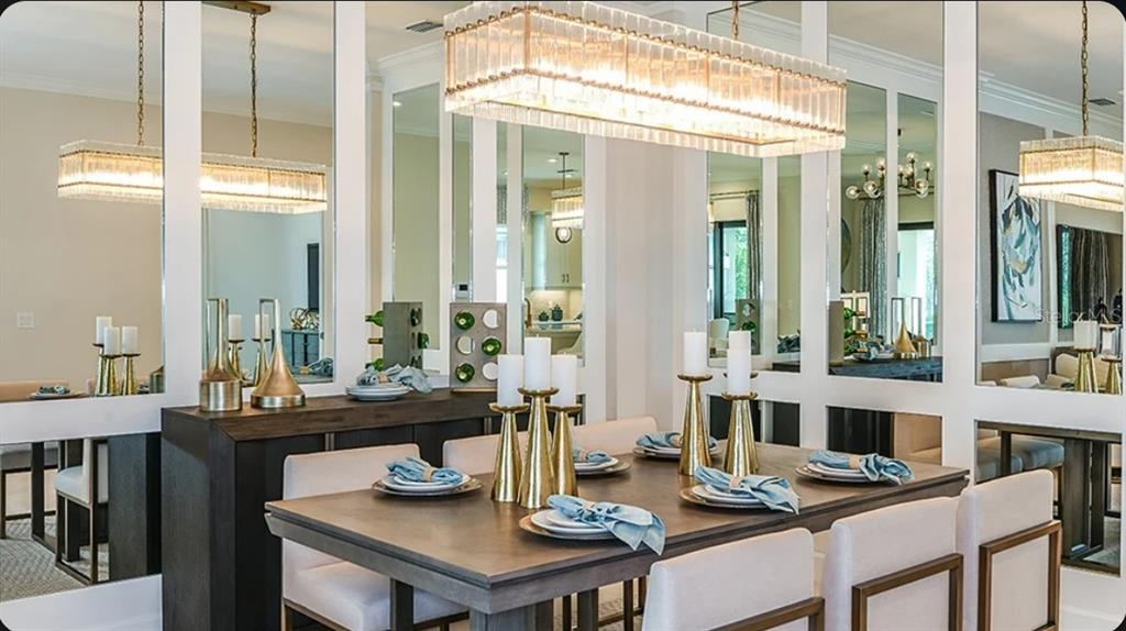 A dining room features a wooden table, upholstered chairs, gold candle holders, and mirrored walls — 3114 VICENZA COURT, BRADENTON, FL