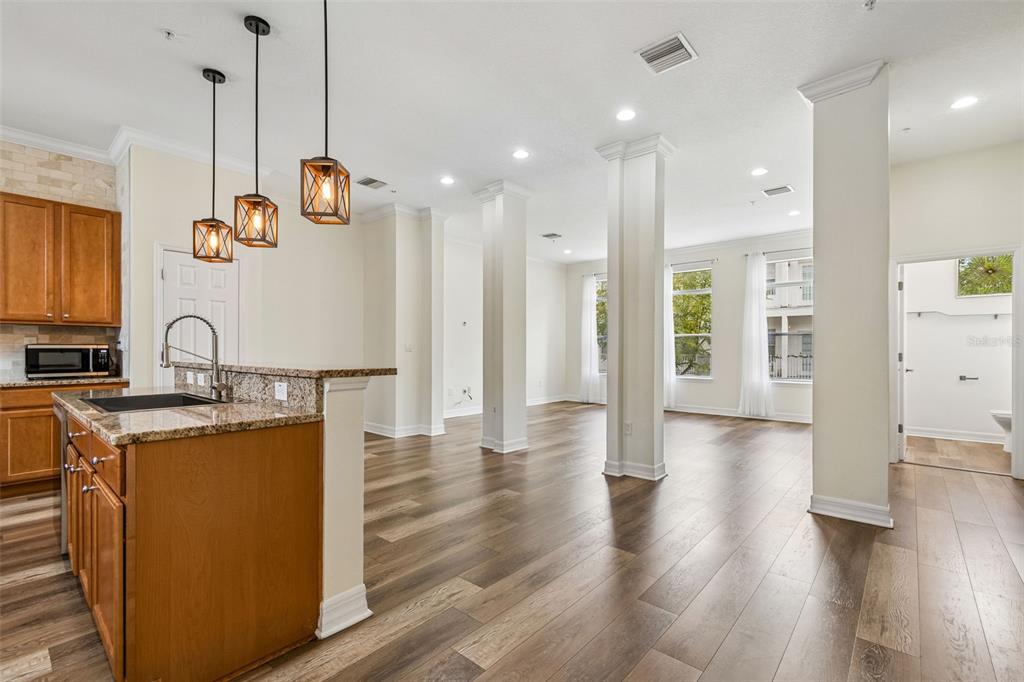 A kitchen with wood cabinets and granite countertops opens to a living area with columns — 4516 BAY SPRING COURT, TAMPA, FL