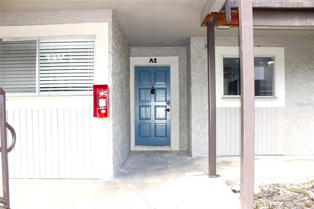 The exterior view shows a blue front door labeled A2 with a red fire extinguisher — 6336 NEWTOWN CIRCLE UNIT 36A2, TAMPA, FL