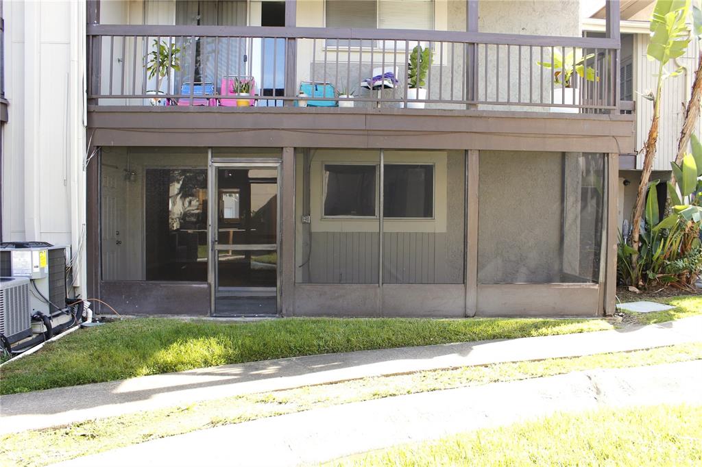 A ground-level screened-in patio sits beneath a second-story balcony with a metal railing — 6336 NEWTOWN CIRCLE UNIT 36A2, TAMPA, FL