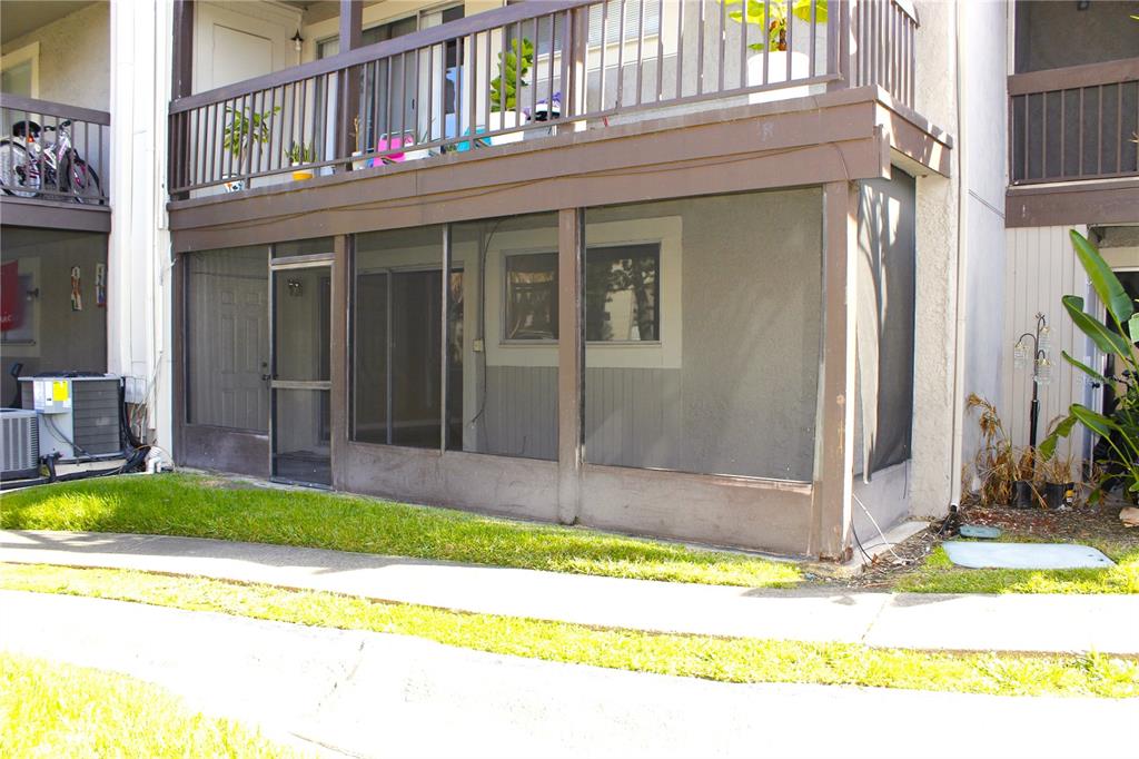A ground-floor apartment patio features a screened-in enclosure and a balcony above — 6336 NEWTOWN CIRCLE UNIT 36A2, TAMPA, FL