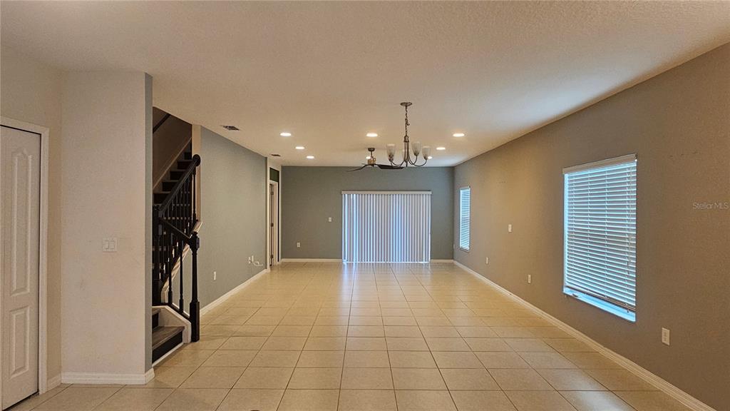 An open-concept living area features light tile flooring, a staircase, and a dining chandelier — 233 PRIMROSE DRIVE, DAVENPORT, FL