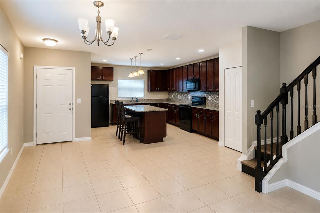 A kitchen with dark wood cabinets, granite countertops, and a central island with bar stools — 233 PRIMROSE DRIVE, DAVENPORT, FL