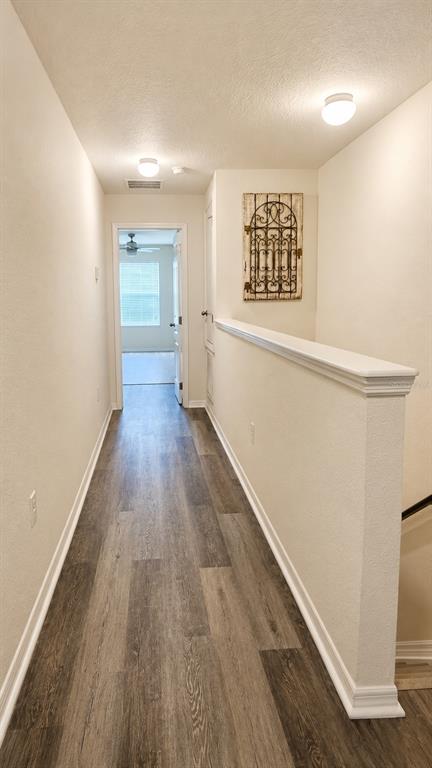 A hallway with wood-look flooring leads to a bedroom, featuring a half-wall and wall decor — 233 PRIMROSE DRIVE, DAVENPORT, FL