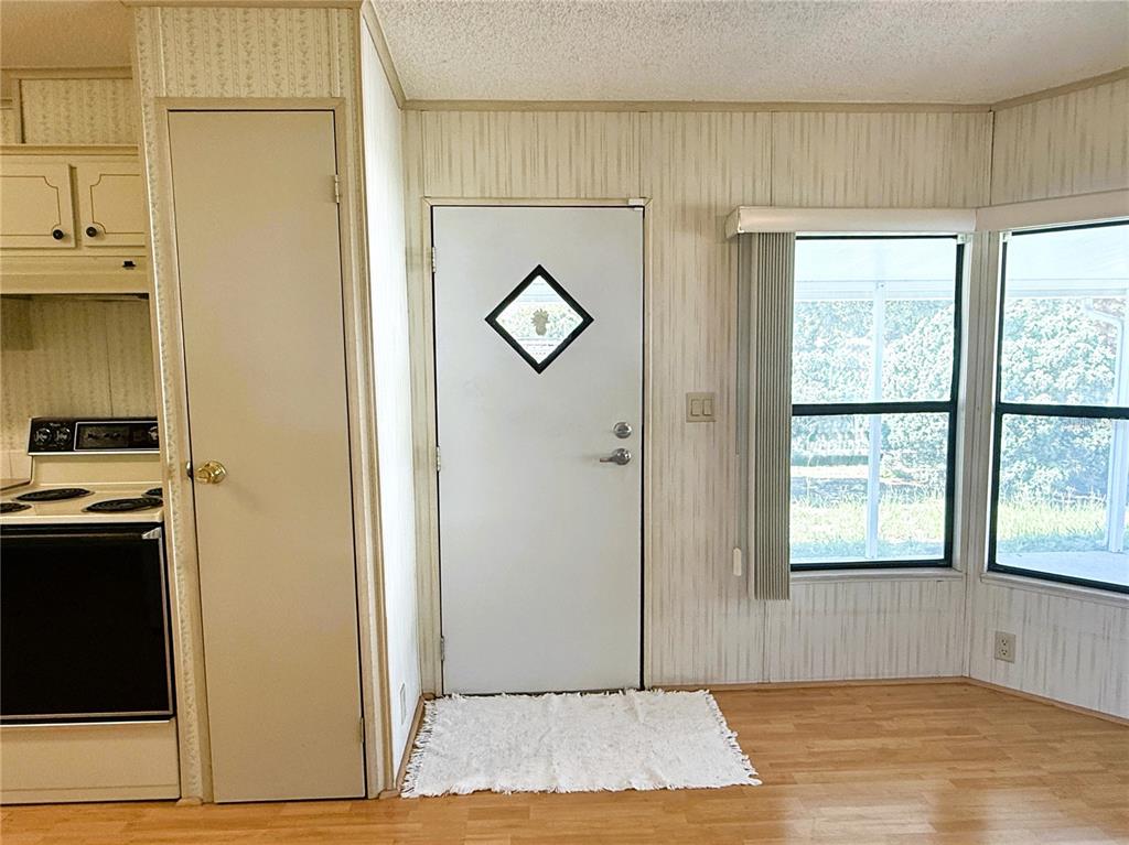 A kitchen area features wood-look flooring, vertical paneled walls, a white door, and a window — 4550 CHARTER STREET, ZEPHYRHILLS, FL