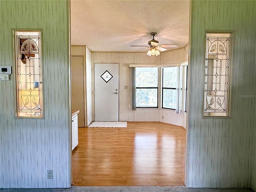 A room with wood-look flooring, a ceiling fan, and two decorative stained-glass window panels — 4550 CHARTER STREET, ZEPHYRHILLS, FL